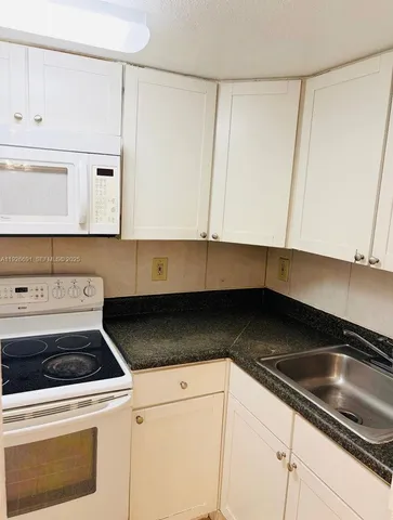 a kitchen with granite countertop white cabinets and a stove