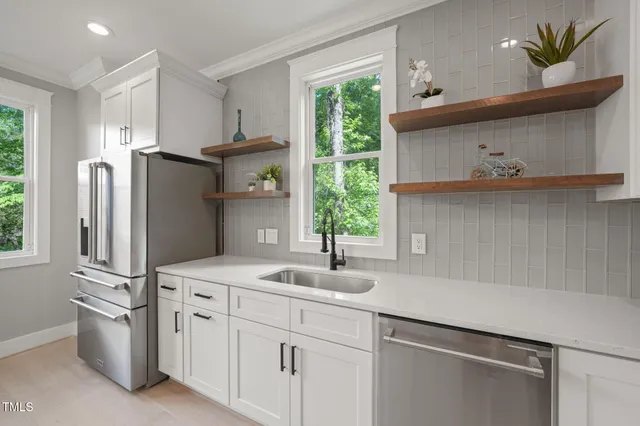 a kitchen with stainless steel appliances a sink a refrigerator and a window