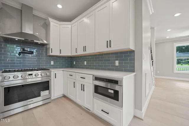 a kitchen with stainless steel appliances granite countertop a stove and white cabinets