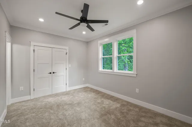 a view of a livingroom with a ceiling fan & windows