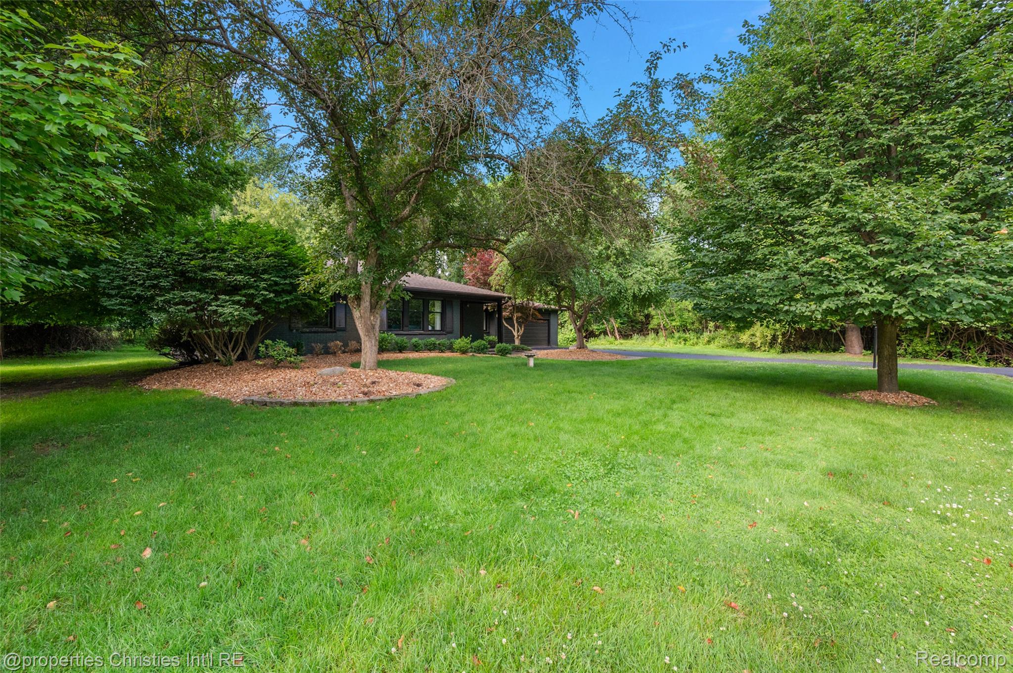 Expansive front lawn featuring mature trees and established landscaping
