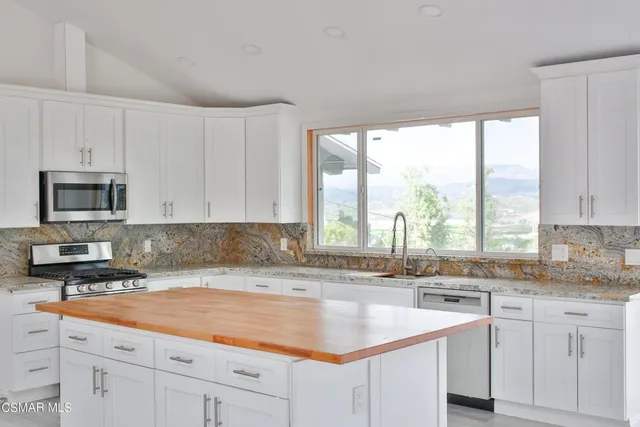 a kitchen with stainless steel appliances granite countertop a sink a stove and white cabinets