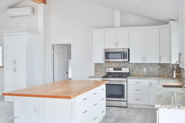 a kitchen with granite countertop white cabinets and stainless steel appliances