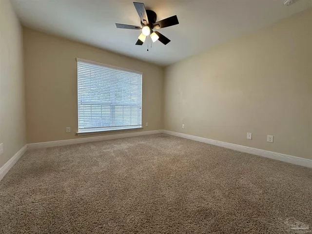 an empty room with windows and ceiling fan