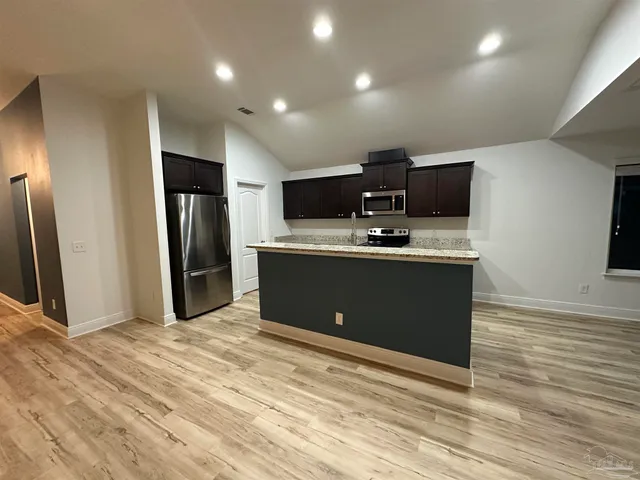 a kitchen with stainless steel appliances granite countertop a sink a stove and a refrigerator