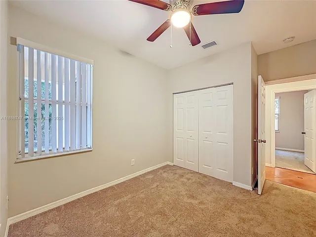 an empty room with windows and fan