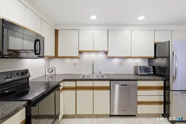 a kitchen with stainless steel appliances granite countertop a sink a stove and a refrigerator