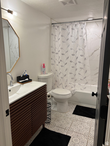 545 23rd Street Ogden, UT 84401 - Photo 27 of 28 Modern bathroom featuring a wood-finish vanity with an integrated sink, patterned floor tiling, and a tiled shower surround