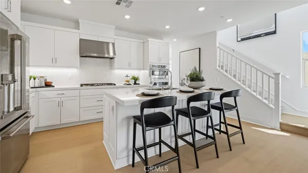 a kitchen with stainless steel appliances kitchen island granite countertop a table chairs sink and cabinets