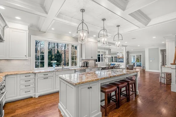 a large kitchen with granite countertop a stove a sink a dining table and chairs