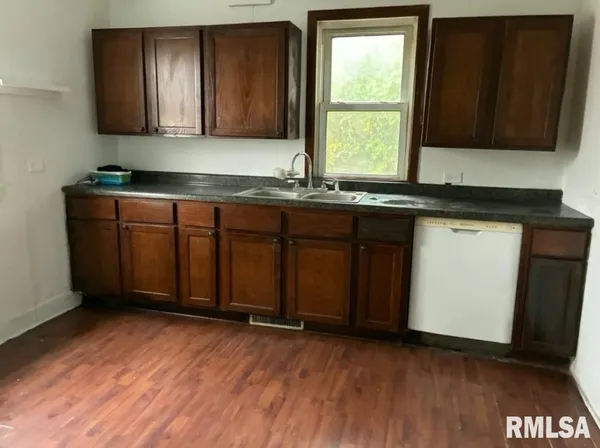 a kitchen with stainless steel appliances granite countertop wooden cabinets a sink and a hard wood floor