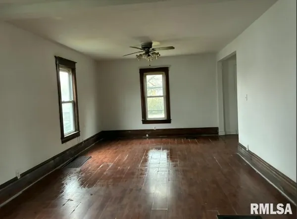 an empty room with wooden floor and windows