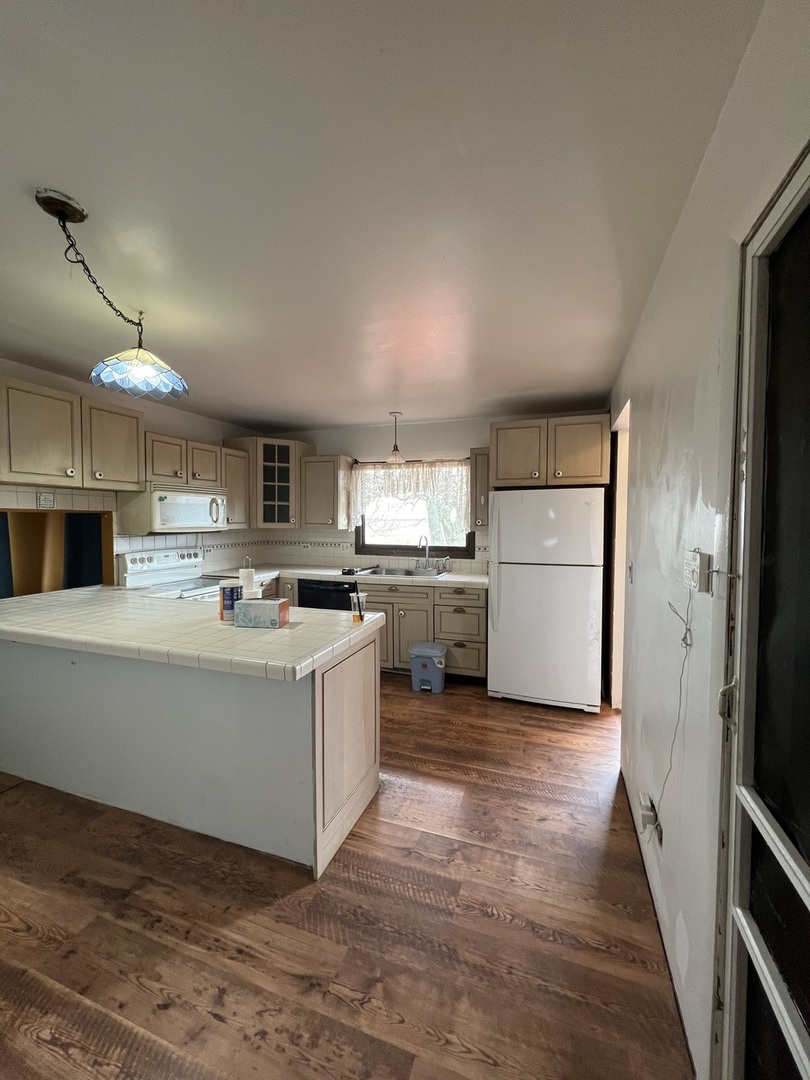 2957 East Kentucky Road Beecher, IL 60401 - Photo 3 of 22 a kitchen with kitchen island a sink a stove a refrigerator and white cabinets