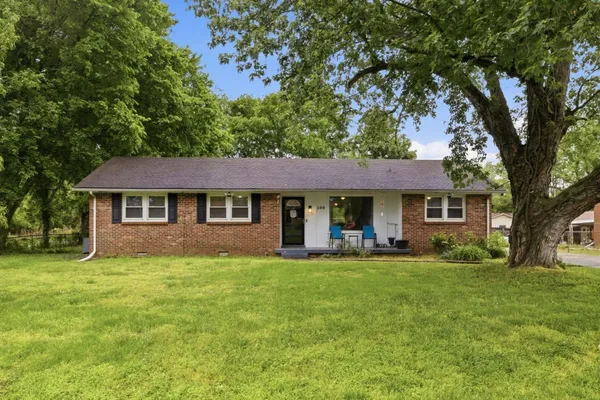 a front view of a house with a garden and trees