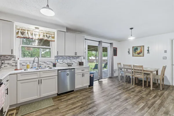 a kitchen with a dining table chairs wooden floor and appliances