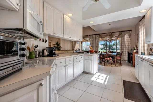 a kitchen with stainless steel appliances kitchen island granite countertop a refrigerator oven a sink dishwasher and white cabinets next to a window