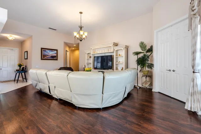 a living room with a bed furniture chandelier and wooden floor