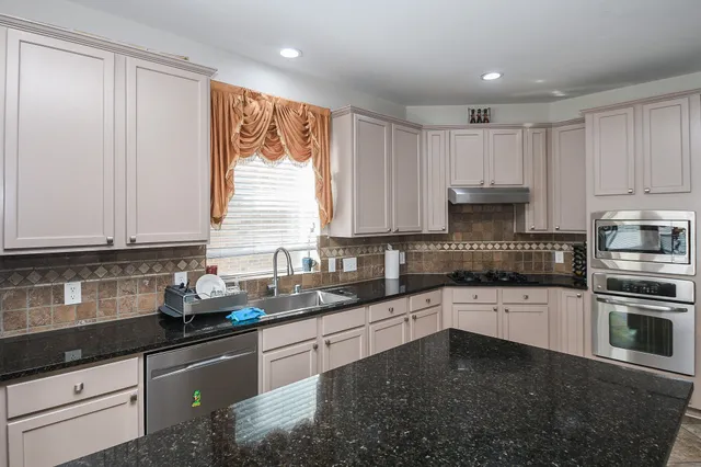 a kitchen with granite countertop a sink stainless steel appliances and cabinets