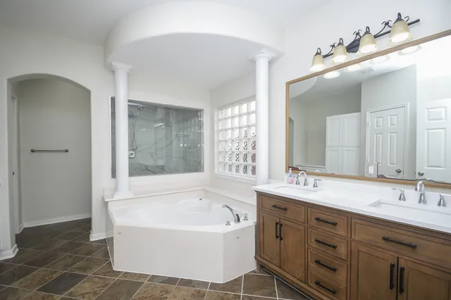 a bathroom with a tub a double vanity sink and mirror
