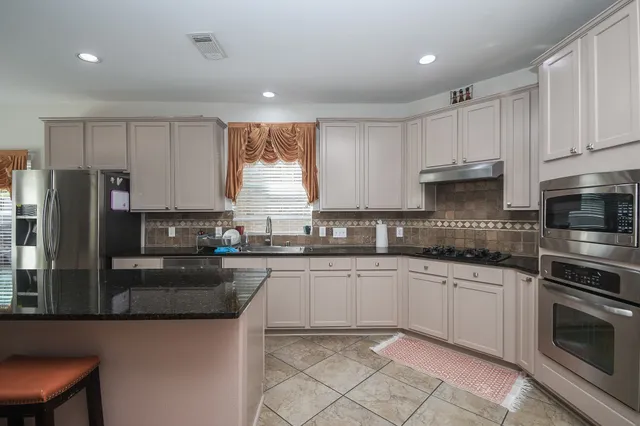 a kitchen with granite countertop a sink stainless steel appliances and cabinets