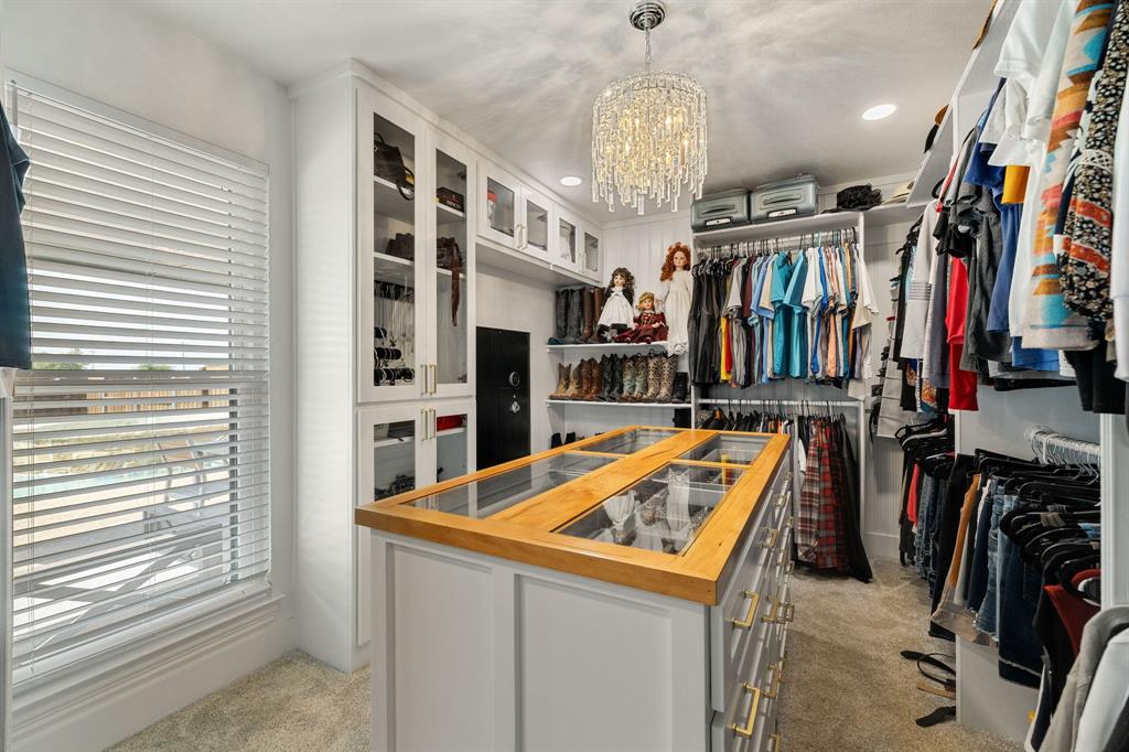12240 Wellington Road Ponder, TX 76259 - Photo 27 of 40 Custom closet system featuring a central island with a wood-finish top and glass inserts, multiple hanging rods, and built-in shelving