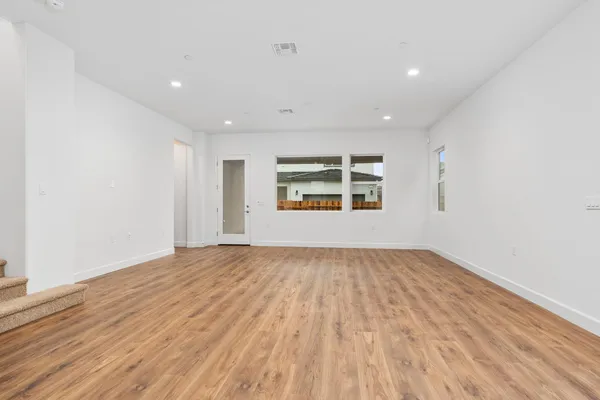 a view of an empty room with window and wooden floor