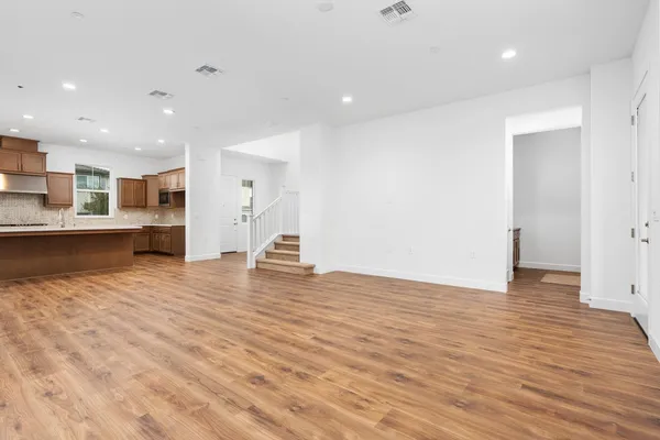 a view of a kitchen with kitchen island a sink wooden floor and a refrigerator