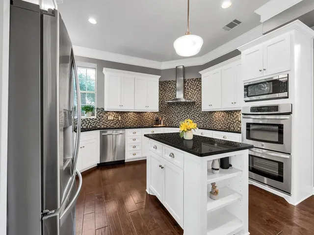 a kitchen with stainless steel appliances kitchen island granite countertop a stove and a sink