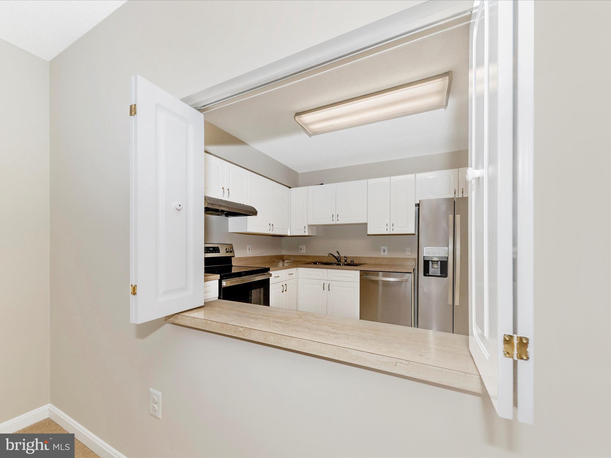 14809 Pennfield Circle, Unit 402 Silver Spring, MD 20906 - Photo 9 of 59 a kitchen with a stove and white cabinets