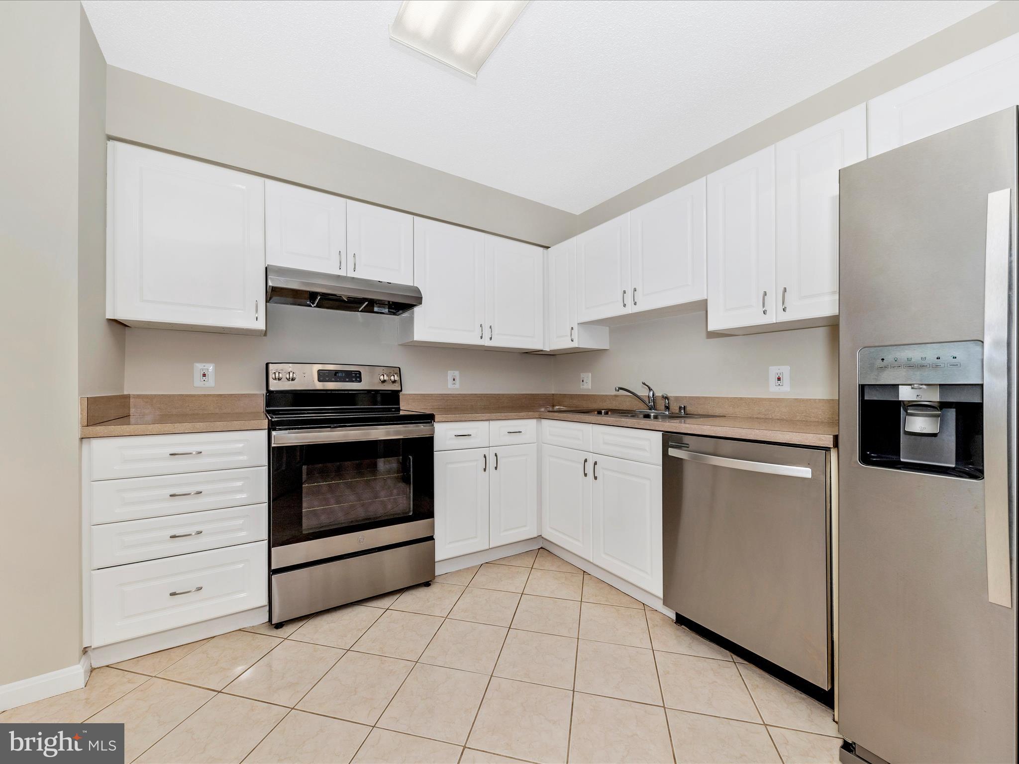 14809 Pennfield Circle, Unit 402 Silver Spring, MD 20906 - Photo 10 of 59 a kitchen with granite countertop white cabinets and appliances