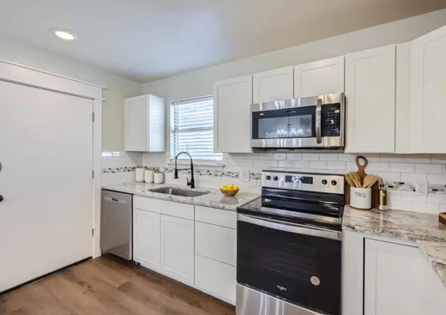 a kitchen with stainless steel appliances granite countertop a sink stove a microwave and cabinets