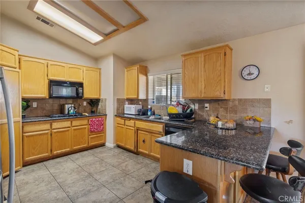 a kitchen with stainless steel appliances granite countertop a refrigerator a stove and a sink with cabinets