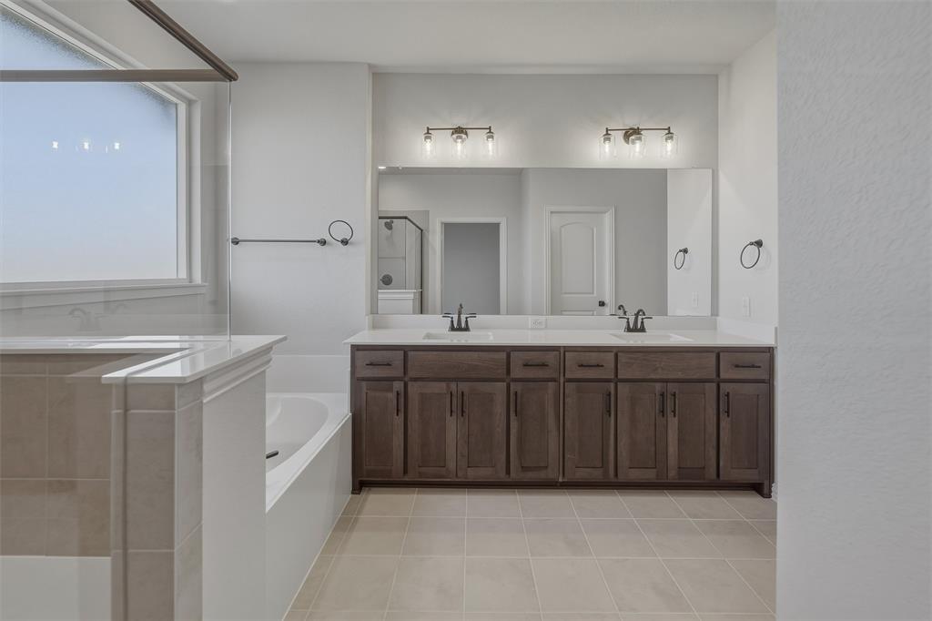 1213 Colca Drive Springtown, TX 76082 - Photo 15 of 23 Bathroom featuring a dual vanity with dark wood-finish cabinetry and light countertops, a large framed mirror, and a built-in soaking tub