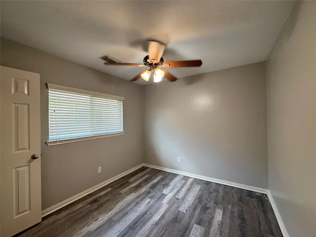 a view of an empty room with a window and wooden floor