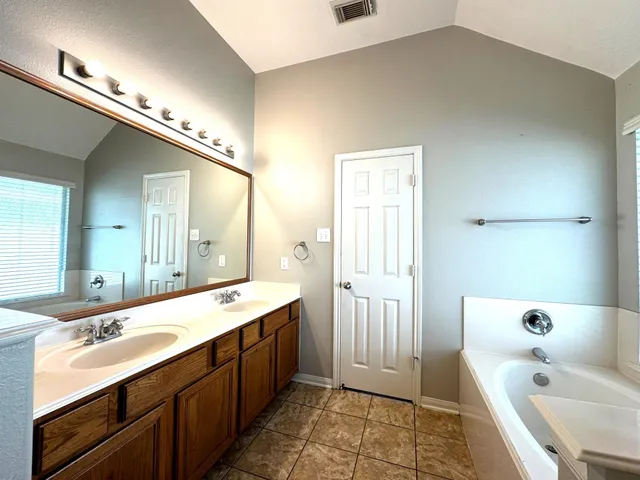 a bathroom with a tub sink and mirror