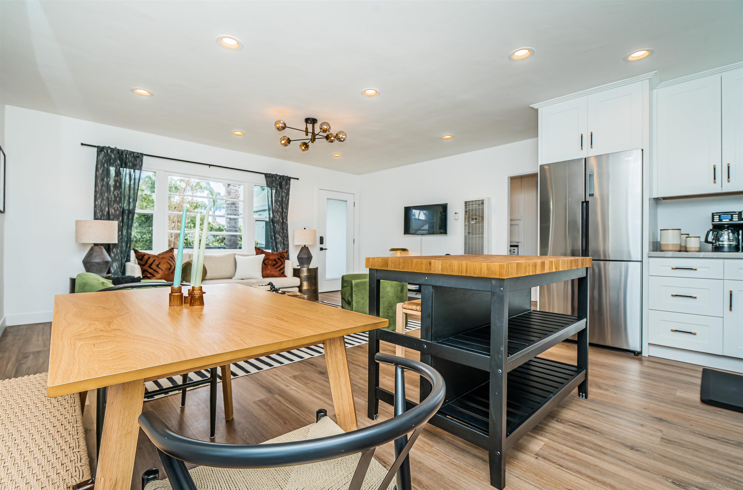 a kitchen with stainless steel appliances kitchen island granite countertop a refrigerator a stove and white cabinets with wooden floors