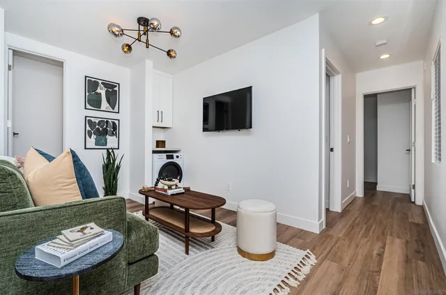 a living room with furniture a flat screen tv and kitchen view