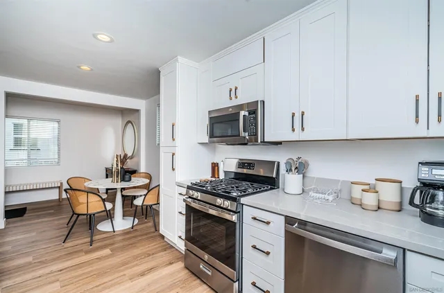 a kitchen with stainless steel appliances granite countertop a stove a sink dishwasher and a microwave with wooden floor