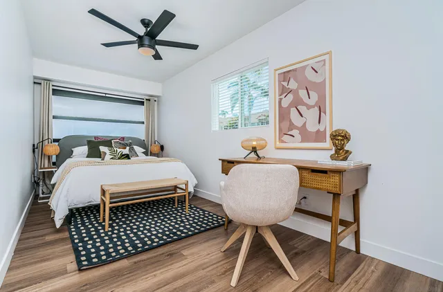 a bed sitting in a bedroom next to a window with a small table