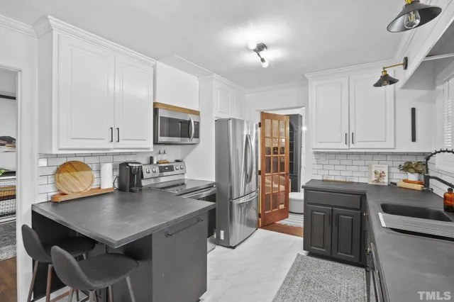 a kitchen with a stove a sink dishwasher a refrigerator with a dining table and chairs