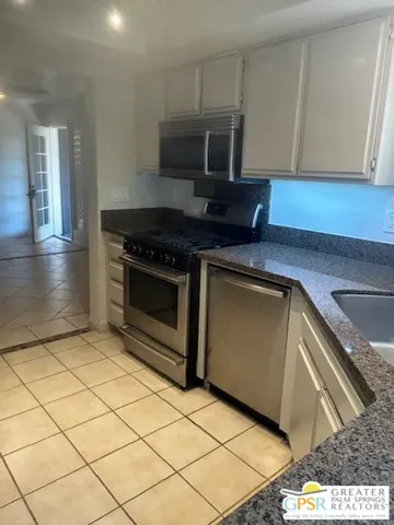 a kitchen with granite countertop a stove top oven a sink a counter space and cabinets