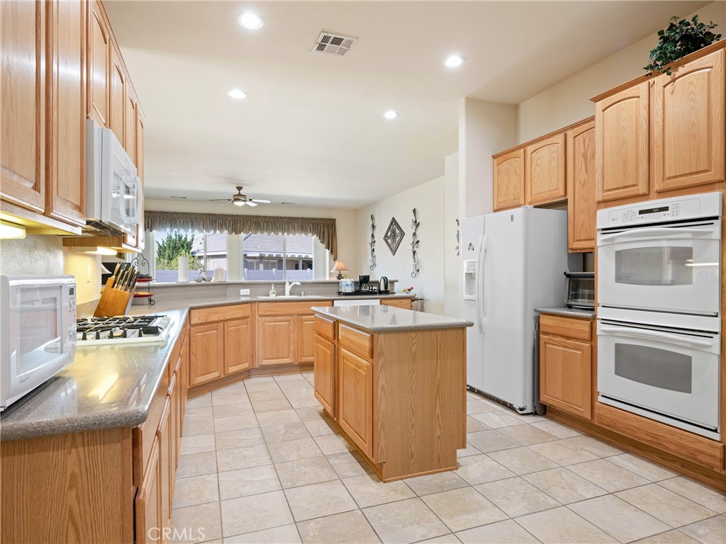 10588 Archerwill Road Apple Valley, CA 92308 - Photo 16 of 35 a kitchen with stainless steel appliances granite countertop a refrigerator a sink dishwasher a oven with white cabinets and wooden floor