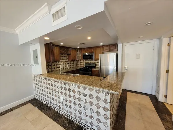 a kitchen with stainless steel appliances kitchen island granite countertop a refrigerator and a sink