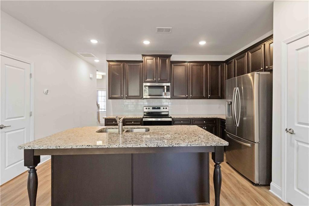 3437 Sumersbe Court Atlanta, GA 30349 - Photo 7 of 25 a kitchen with kitchen island granite countertop stainless steel appliances a refrigerator stove microwave and cabinets