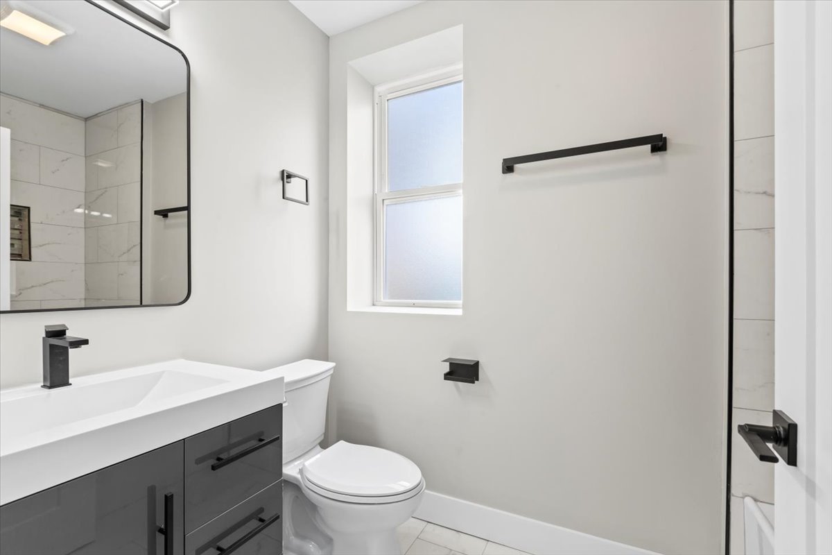 6128 South Rhodes Avenue, Unit 1 Chicago, IL 60637 - Photo 8 of 12 a bathroom with a sink a toilet a mirror and shower