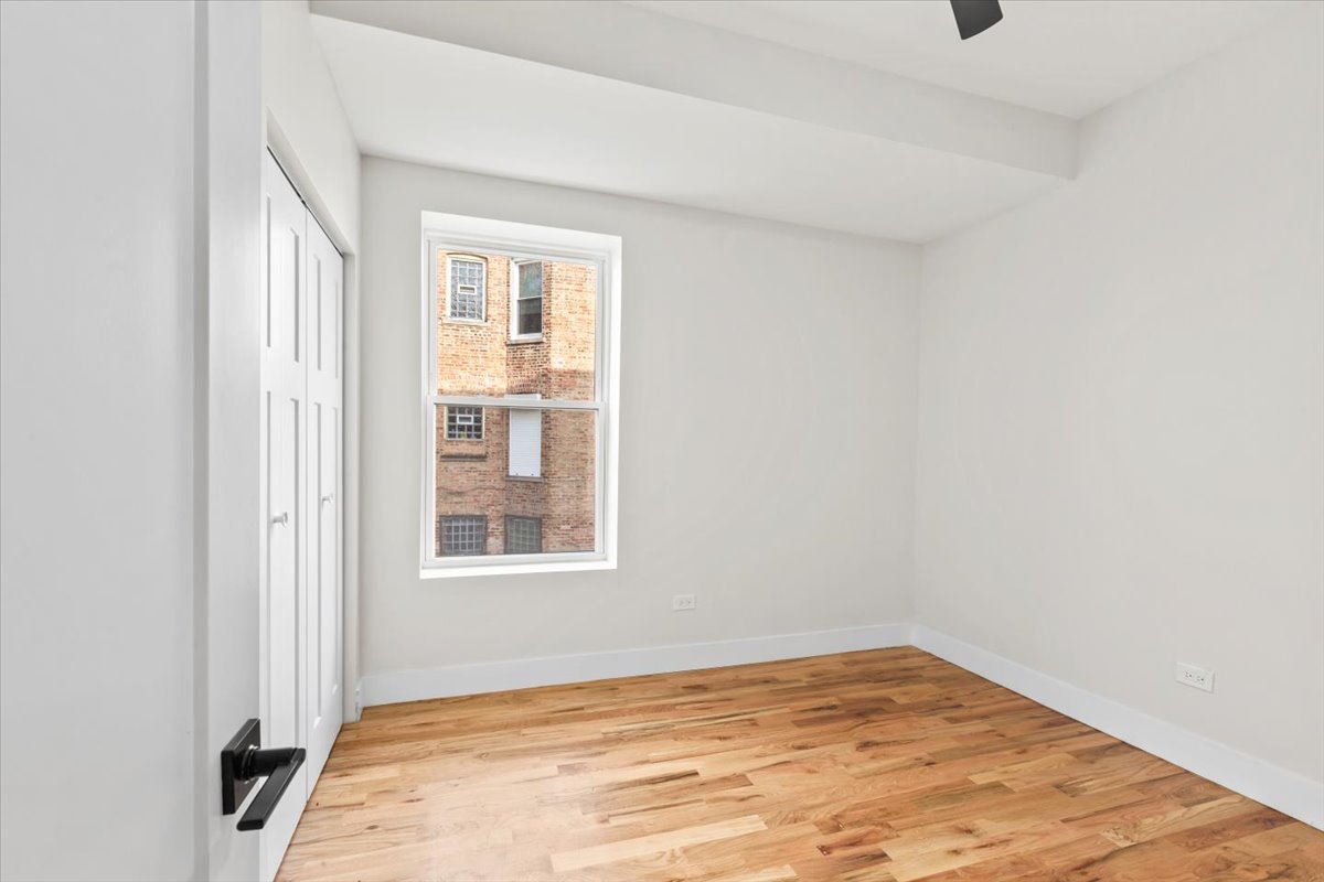 6128 South Rhodes Avenue, Unit 1 Chicago, IL 60637 - Photo 10 of 12 a view of an empty room with wooden floor and a window
