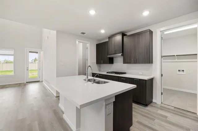 a kitchen with a sink a stove a refrigerator and a cabinets