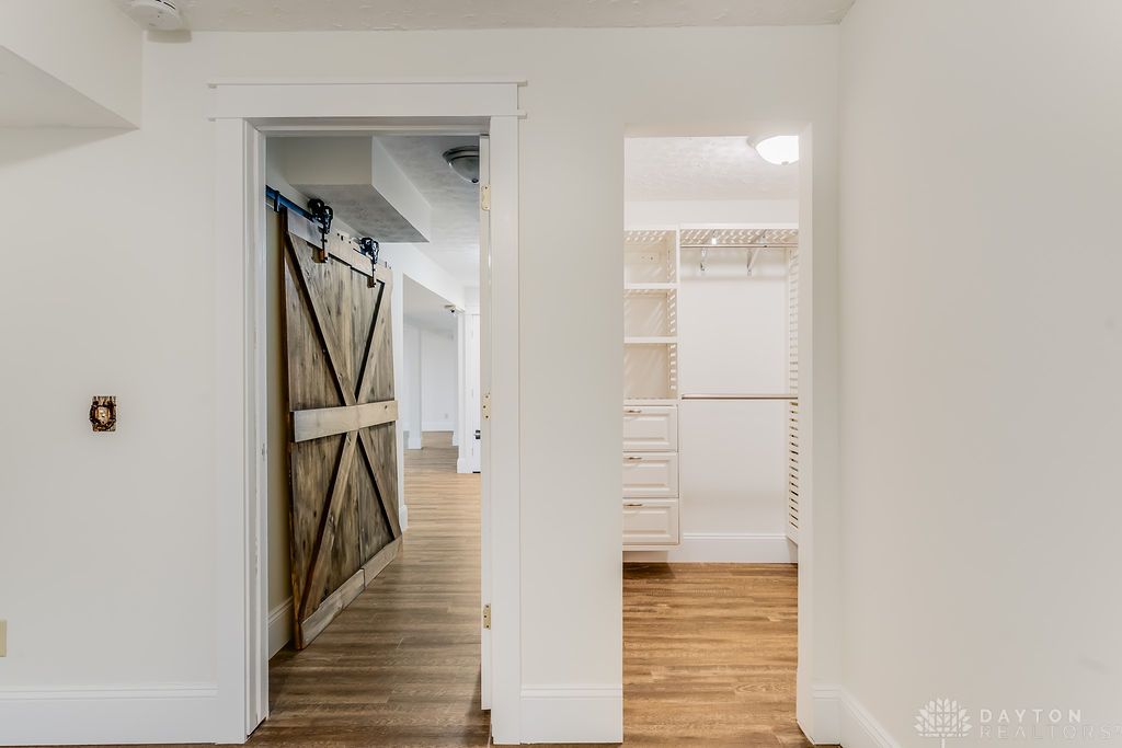 7400 Cook-Jones Road Waynesville, OH 45068 - Photo 51 of 72 This interior hallway features a barn door and built-in closet organization, offering both character and convenience.