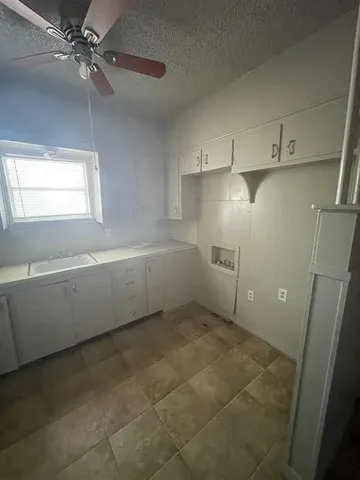 a view of a kitchen with white cabinets and a window