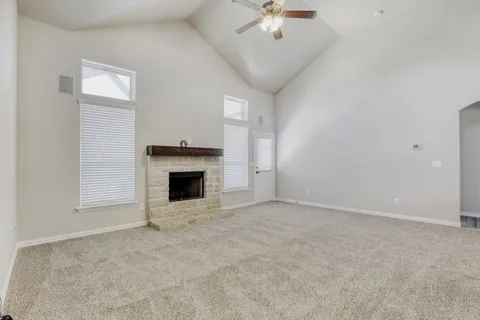 an empty room with a fireplace and chandelier fan